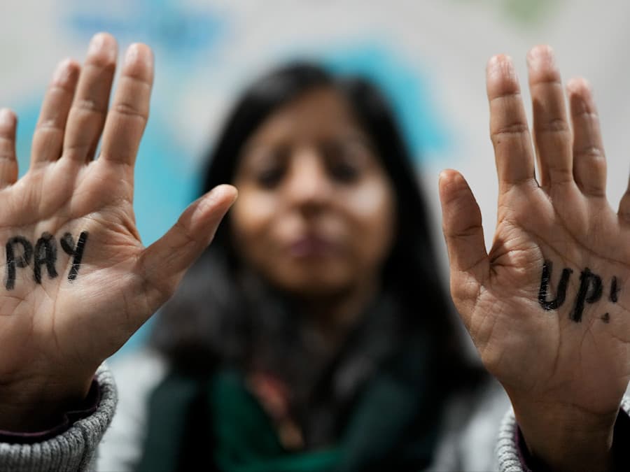 Woman protesting with "Pay up!" legend on her hands