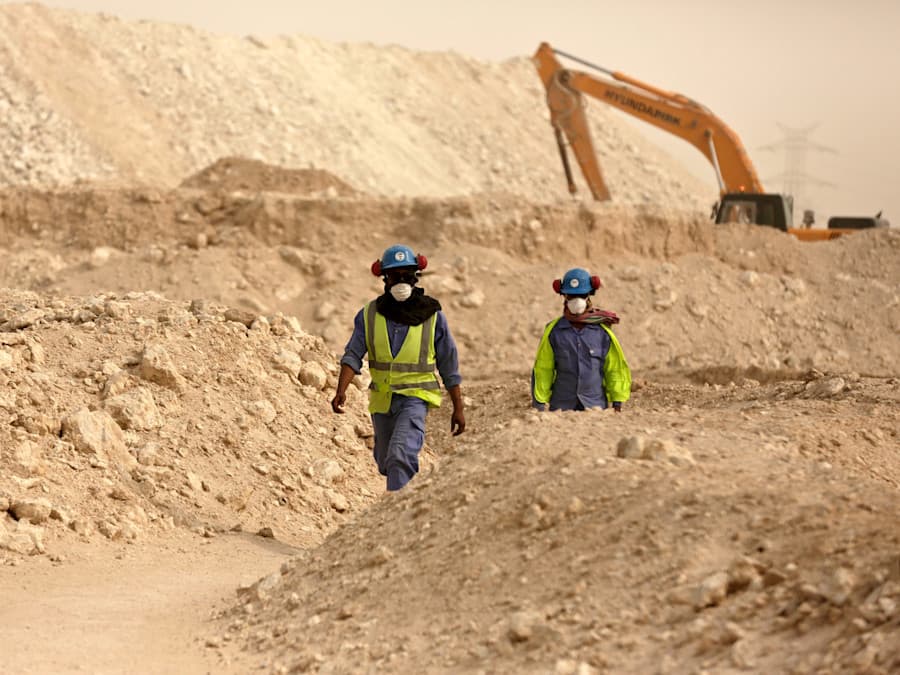Two workers surrounded by desert and construction gear.