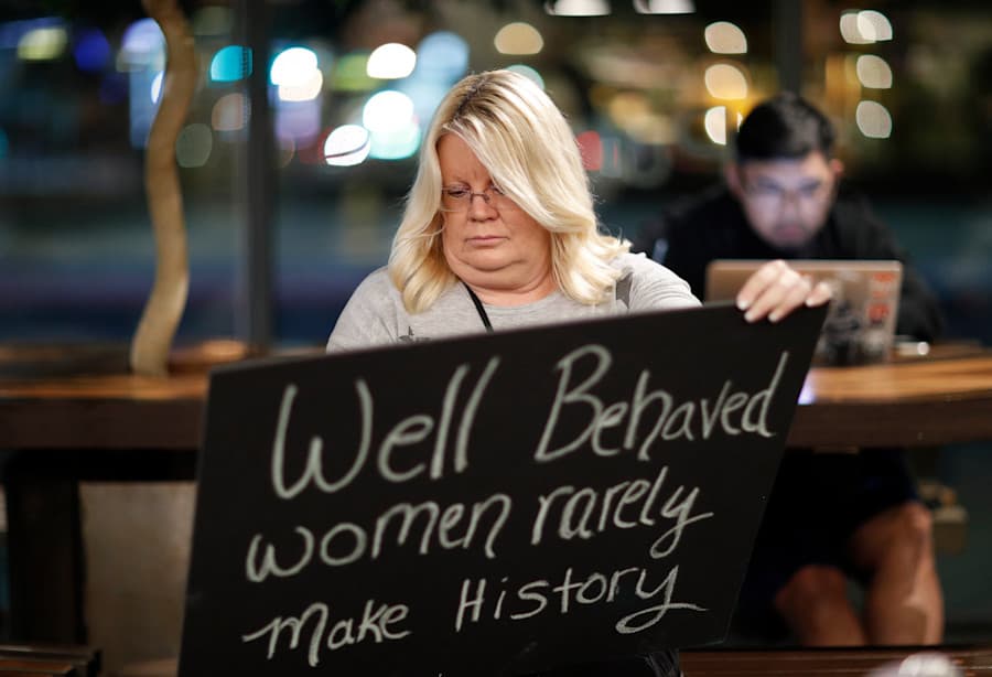 Woman holding a sign with legend "Well behaved women rarely make history"