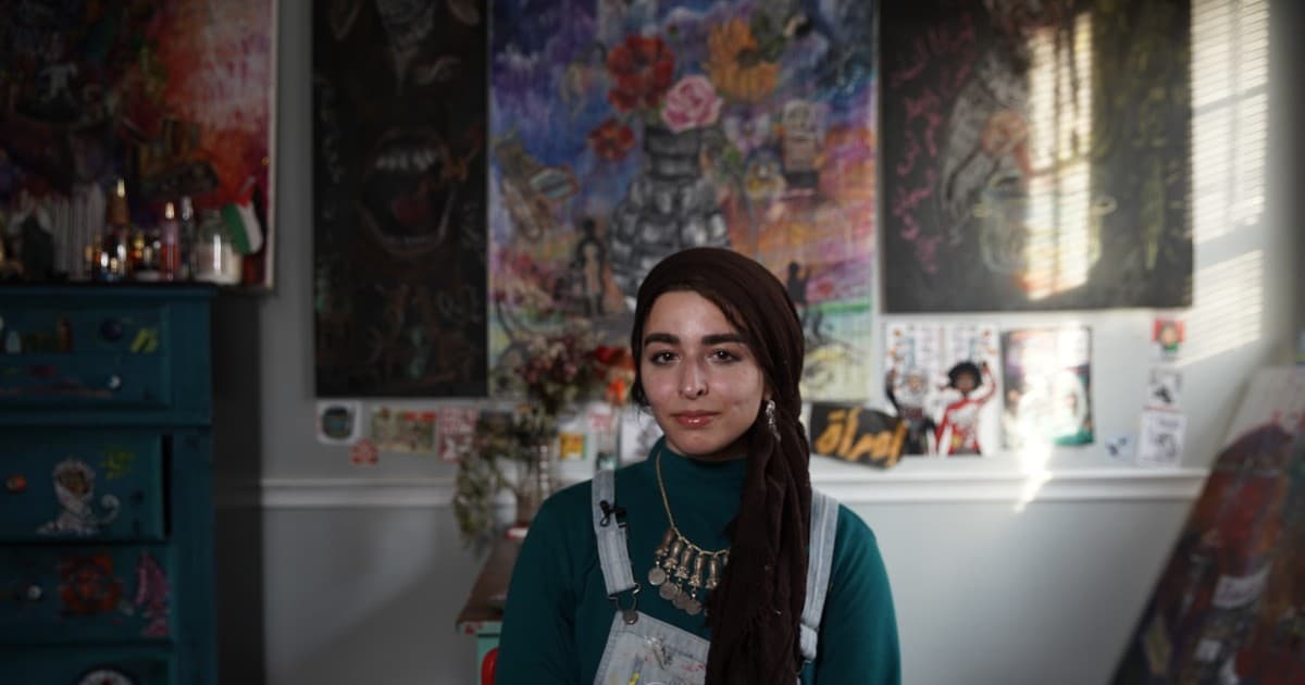 Jenin Yaseen poses in her apartment surrounded by her artwork.